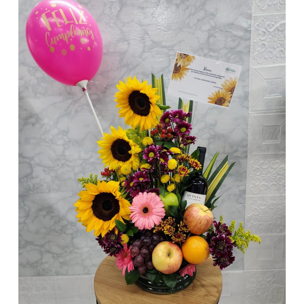 Arreglo de flores con frutas y vino